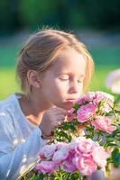 Little adorable girl smelling colorful flowers at summer day photo