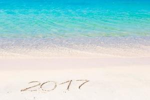 2017 handwritten on sandy beach with soft ocean wave on background photo