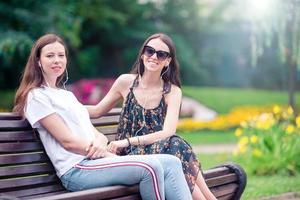 Best friends sitting on a bench in a summer park photo