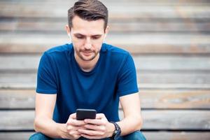 Man is reading text message on mobile phone while walking in the park photo