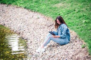 Relaxed young woman reading book in park photo