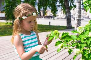 Little adorable girl near white flowers in the garden photo