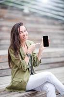Happy woman with smartphone outdoors in the city photo
