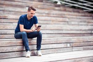 Man is reading text message on mobile phone while walking in the park photo