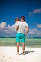 Back view of little girl hugging with dad on the beach photo