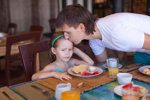 padre besa a su hija antes del desayuno en el restaurante