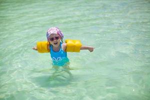 linda niña feliz en traje de baño se divierte en el mar foto