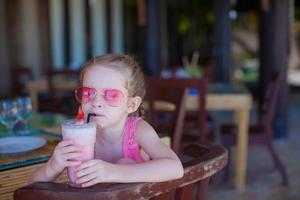 adorable niña desayunando y bebiendo cóctel de frutas foto