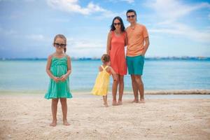 Young beautiful family with two daughters having fun at beach photo