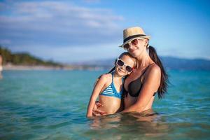 hermosa joven madre y su adorable hijita en la playa foto