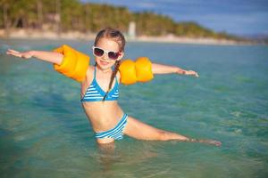 Adorable little girl have fun in the sea on tropical beach vacation photo