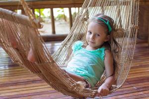 Little cute girl in a hammock on the terrace of her house photo