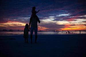 silueta de papá e hijas al atardecer en la playa de boracay foto