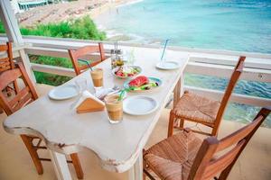 Traditional lunch with delicious fresh greek salad, frappe and brusketa served for lunch at outdoor cafe photo