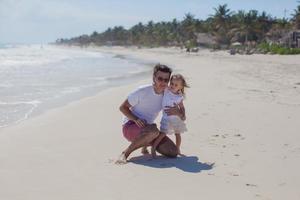 padre feliz con lindas hijas caminando en vacaciones en la playa tropical foto