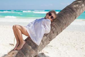 linda niña tendida en una palmera en la playa perfecta foto