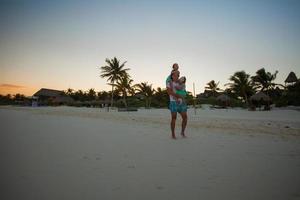 silhouette of father and his two little daughters in the sunset on the beach in Tulum, Mexico photo