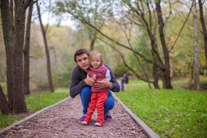 Young father with his cute little daughter in autumn park photo