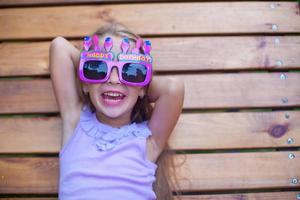 Adorable little girl in Happy Birthday glasses have fun outdoor photo