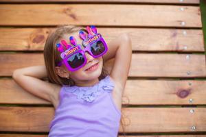 Adorable little girl in Happy Birthday glasses have fun outdoor photo