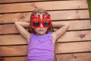 adorable niña con gafas con las palabras feliz cumpleaños al aire libre foto