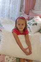 Little girl sitting in a big colorful bed photo