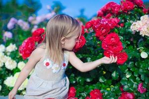 niña adorable sentada cerca de flores de colores en el jardín foto