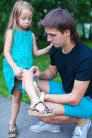 Young father pities his little daughter, who hurt her leg photo