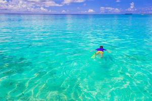 Young man snorkeling in clear tropical turquoise waters photo