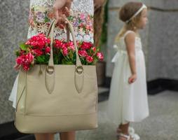 Small red charming roses in fashion women's bag in wedding photo