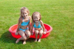 dos hermanitas en una piscina pequeña se divierten foto