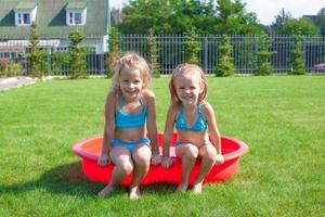 Two little sisters frolicing and splashing in their yard photo