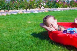 retrato de una niña encantadora y relajante disfrutando de sus vacaciones en una piscina pequeña foto