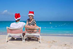 Back view of couple in Santa hats enjoy beach vacation photo