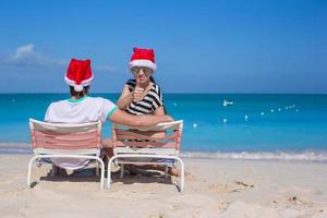 pareja joven con sombreros de santa durante las vacaciones en la playa foto