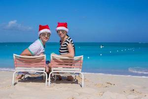 pareja joven con sombreros de santa durante las vacaciones en la playa foto