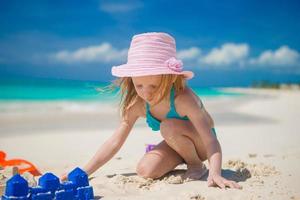 Little girl playing with beach toys during tropical vacation photo