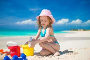 Adorable little girl playing with toys on beach vacation photo