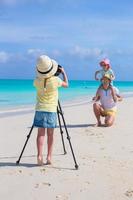 Little girl making photo of her dad and sister at the beach