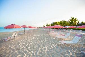 Paradise view of tropical empty sandy plage with umbrella and beach chair photo