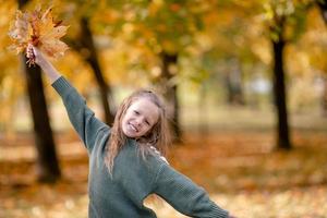 Portrait of adorable little girl with yellow leaves bouquet in fall photo