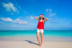 bella joven con sombrero de santa en una playa tropical foto