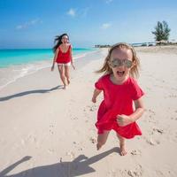 Young mother and little girl running at tropical beach photo