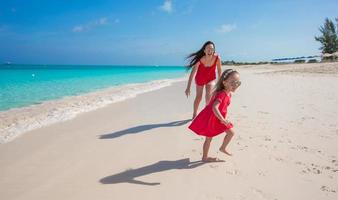 Young mother and little girl running at tropical beach photo