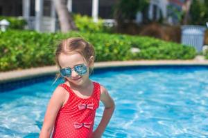 Little cute happy girl swims in the swimming pool photo