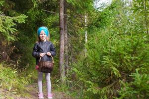 Little happy girl pick up mushrooms in autumn forest photo