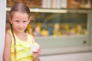 adorable niña comiendo helado al aire libre en verano. lindo niño disfrutando del verdadero helado italiano cerca de heladería en roma foto