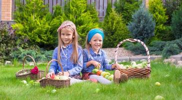 dos niñas felices con gran cosecha otoñal de tomates en cestas foto