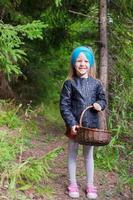 niña feliz recoger setas en el bosque de otoño foto