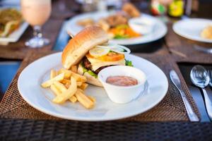 Classic burger with French fries on table in outdoor cafe photo